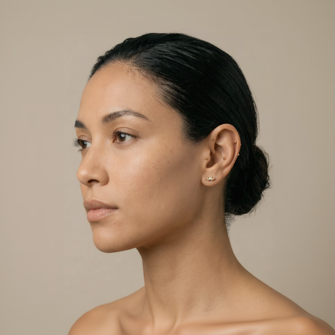 woman with black hair wearing gold diamond stud earring