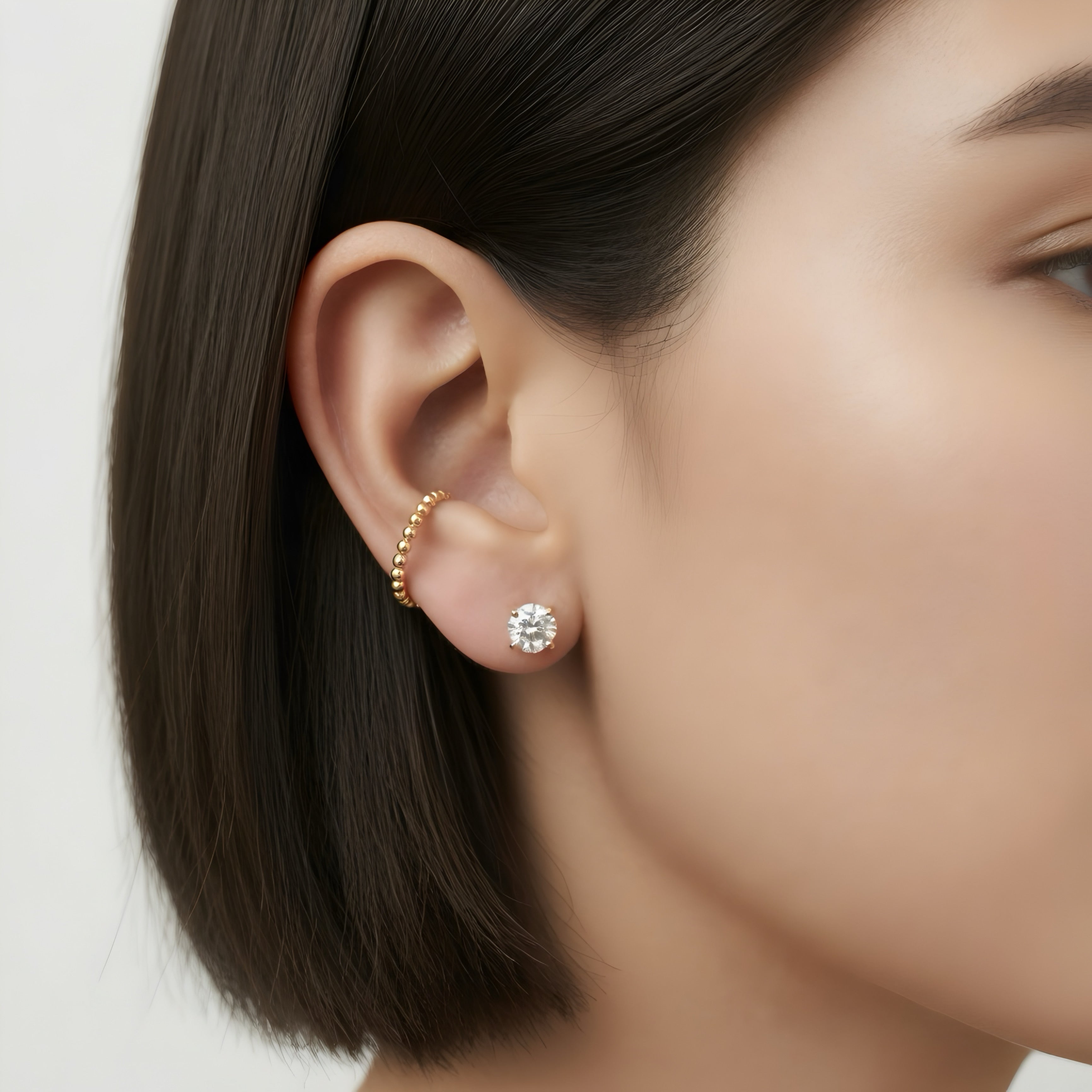 woman wearing diamond stud and gold ear cuff