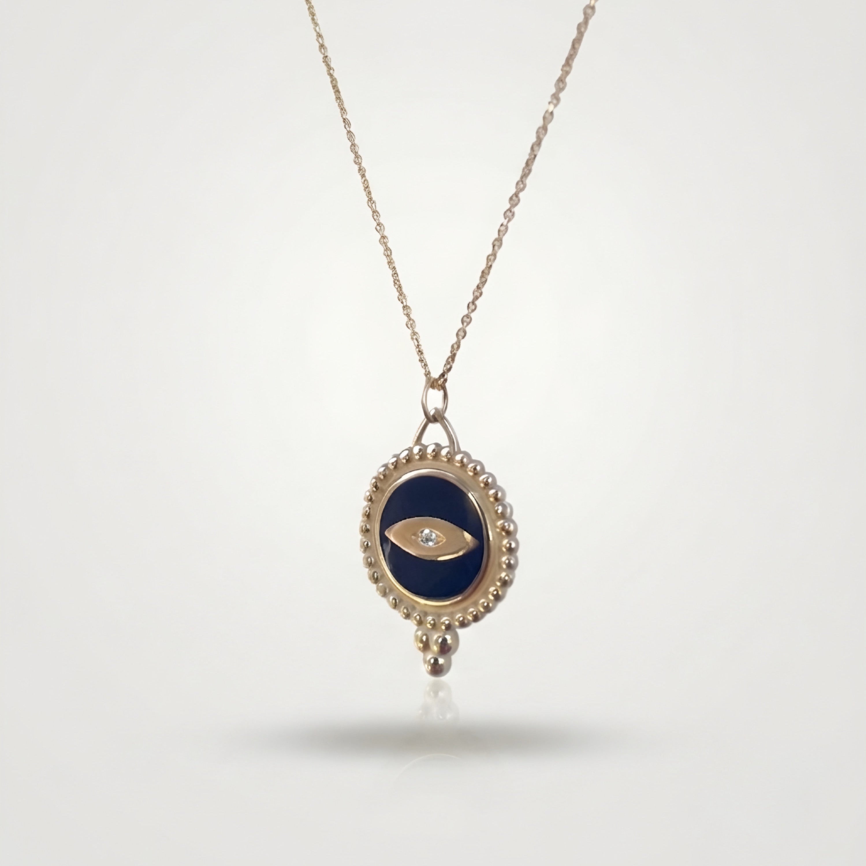 Necklace with a pendant featuring an eye design with dark blue enamel and a central small natural diamond on a white background