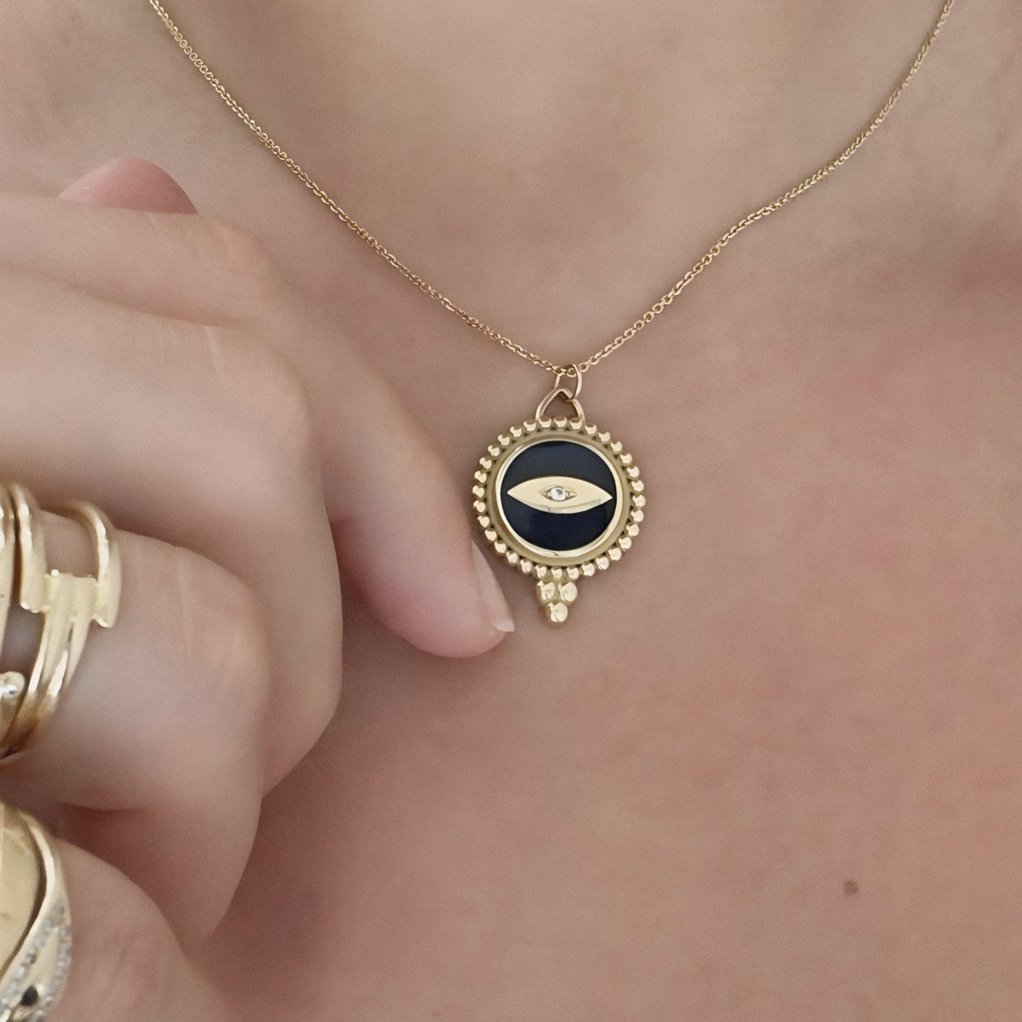 Gold necklace with an eye pendant worn by a person