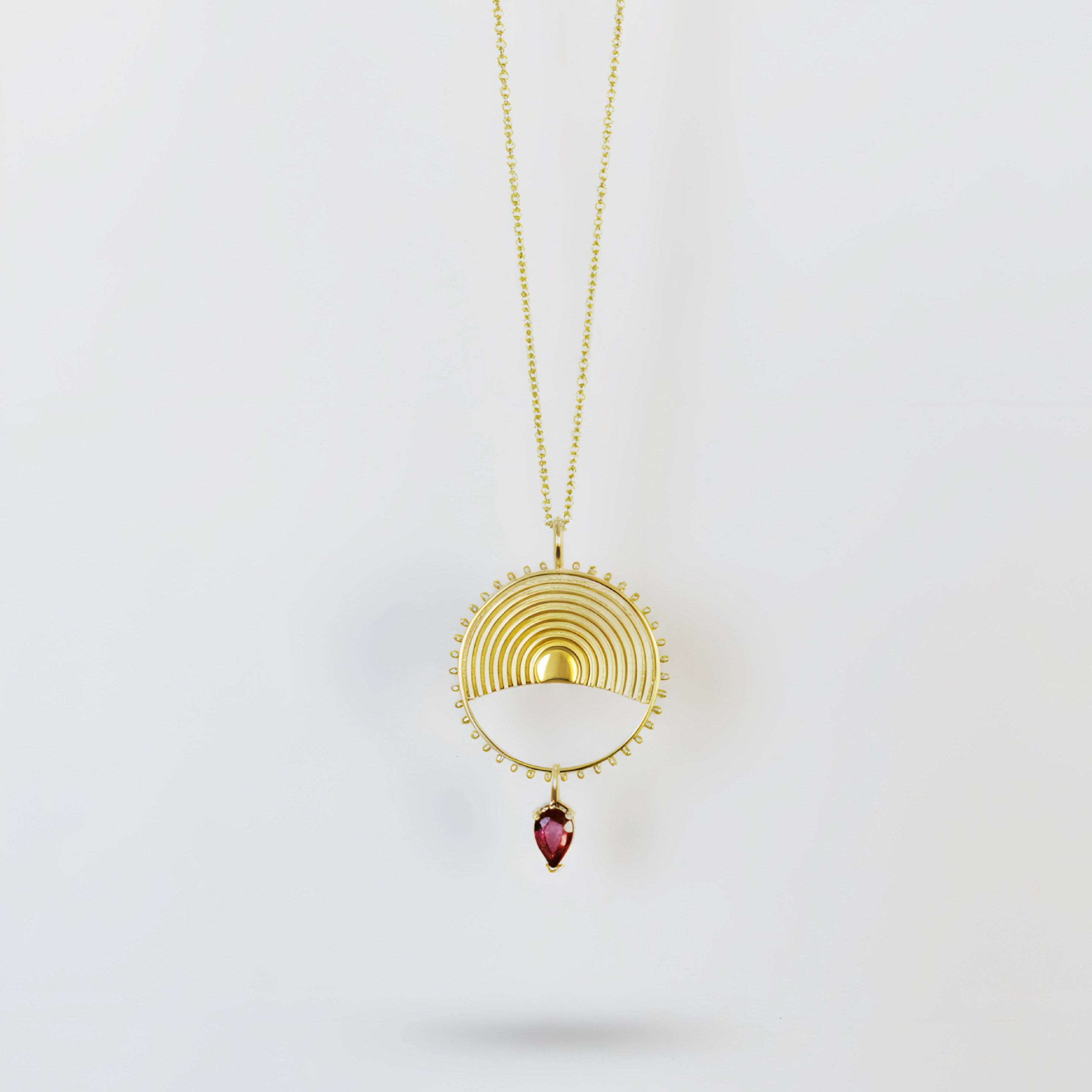 Gold circular pendant on chain with pear drop tourmalime gemstone