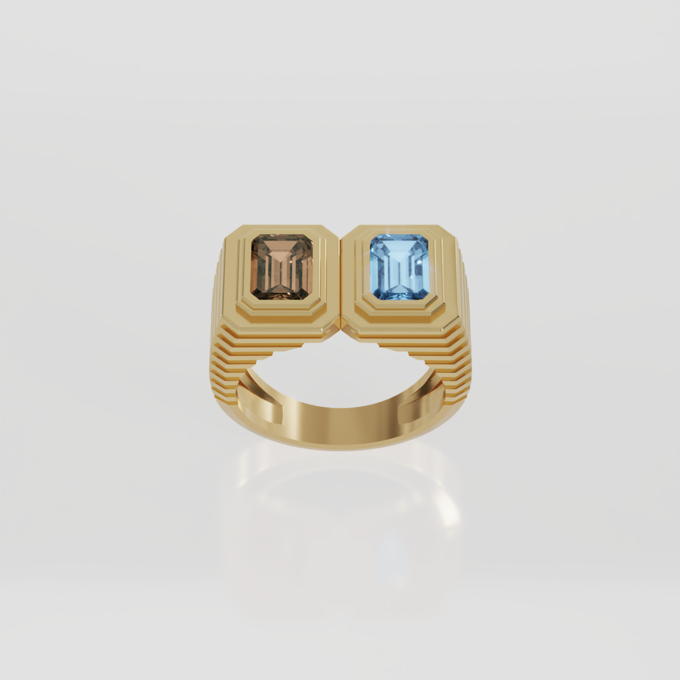 A gold signet ring featuring two rectangular gemstones, one brown and one light blue, set against a light gray background with a soft reflection.