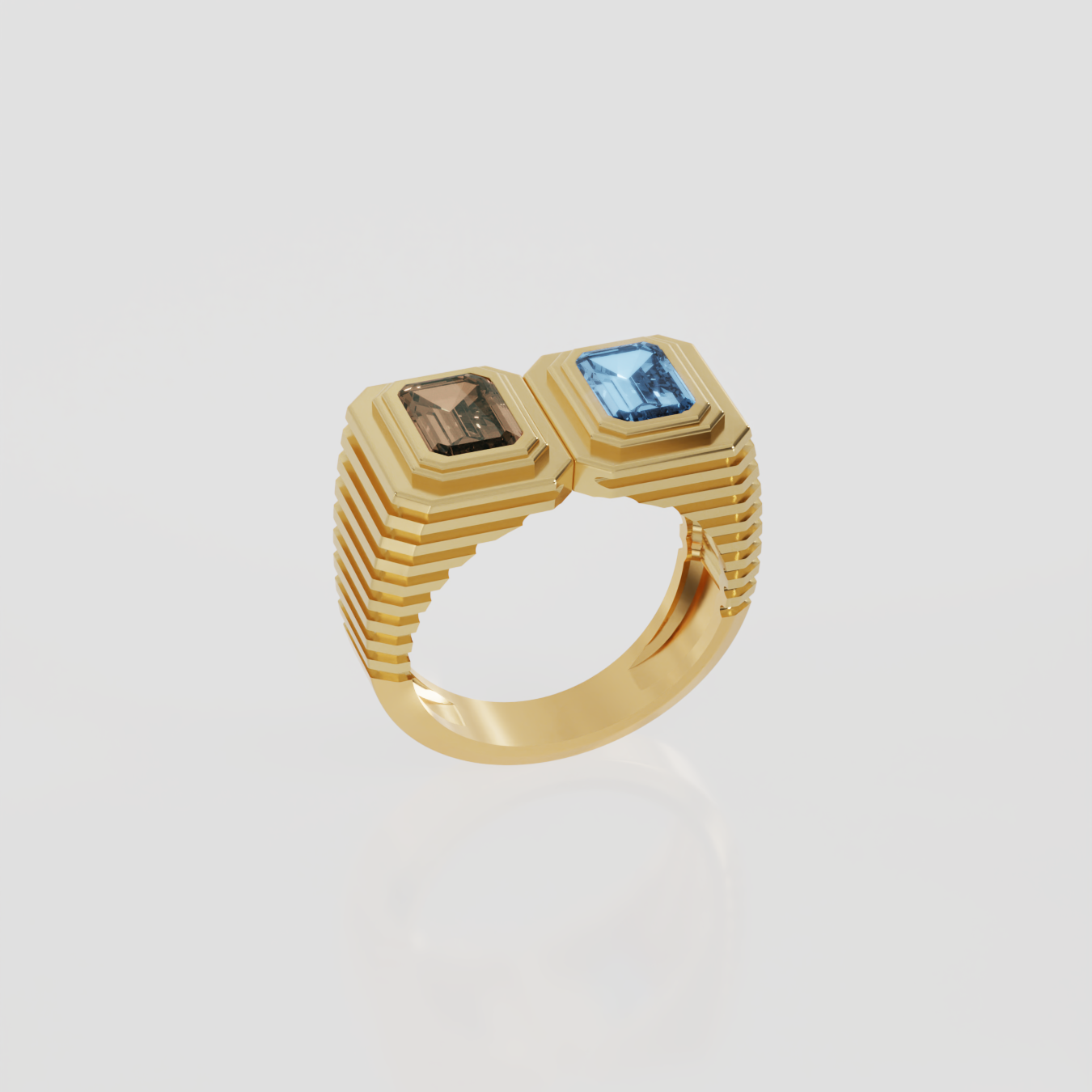 A gold signet-style ring with a ribbed band and two rectangular gemstones, one light blue and one brown, set against a light gray background.